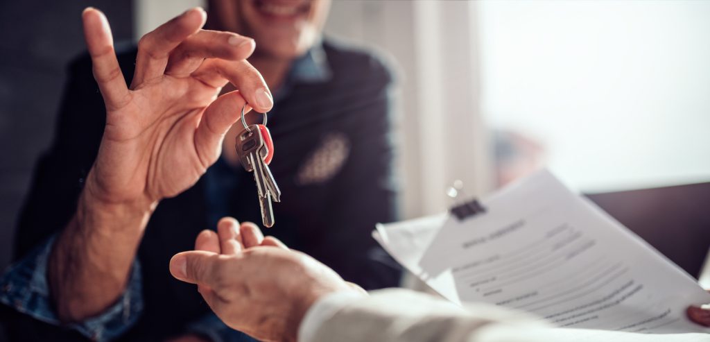 close-up-of-commercial-real-estate-agent-passing-keys-to-client-who-is-holding-lease-agreement
