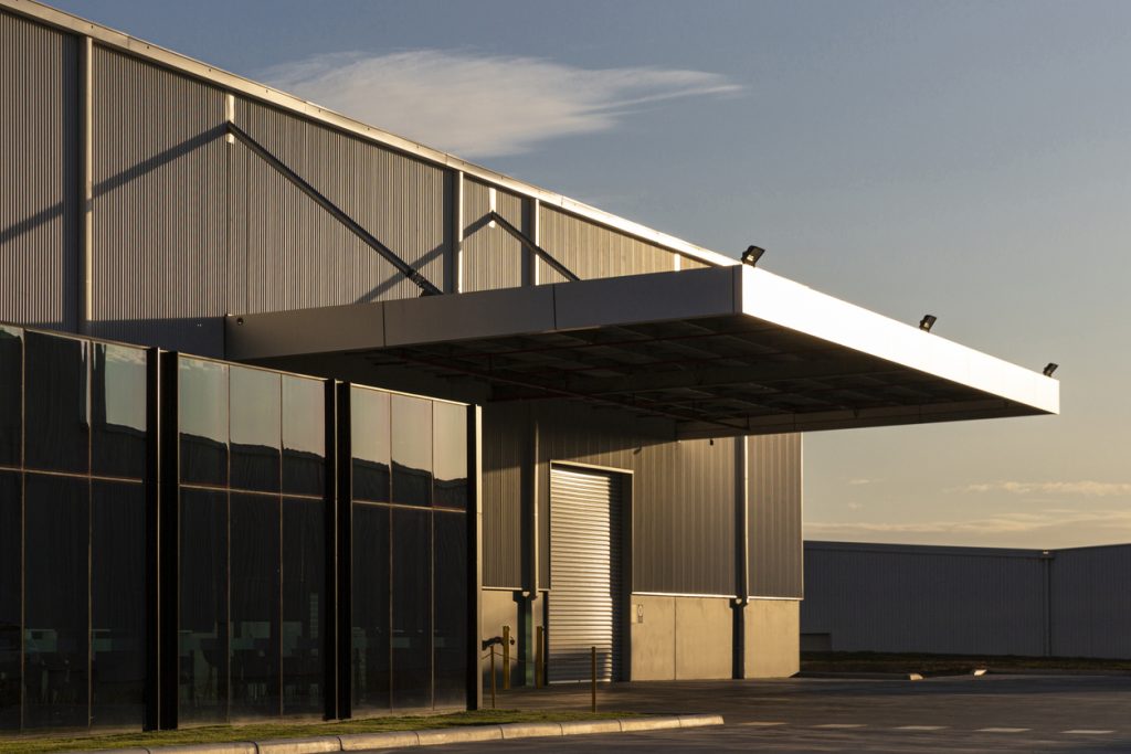 An industrial warehouse with a large overhang awning over the door at sunset.